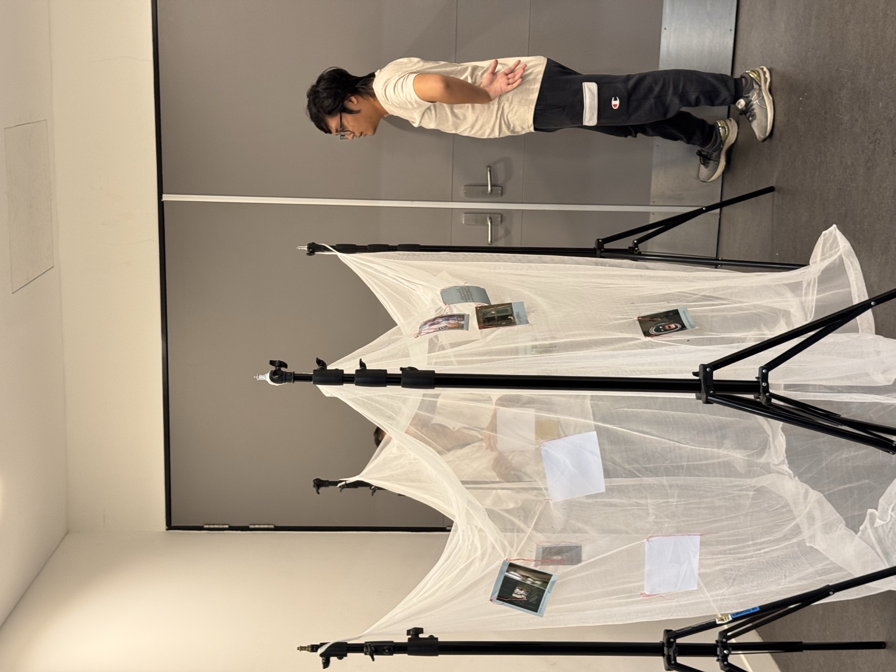 A white fabric-net installation suspended against a black wall