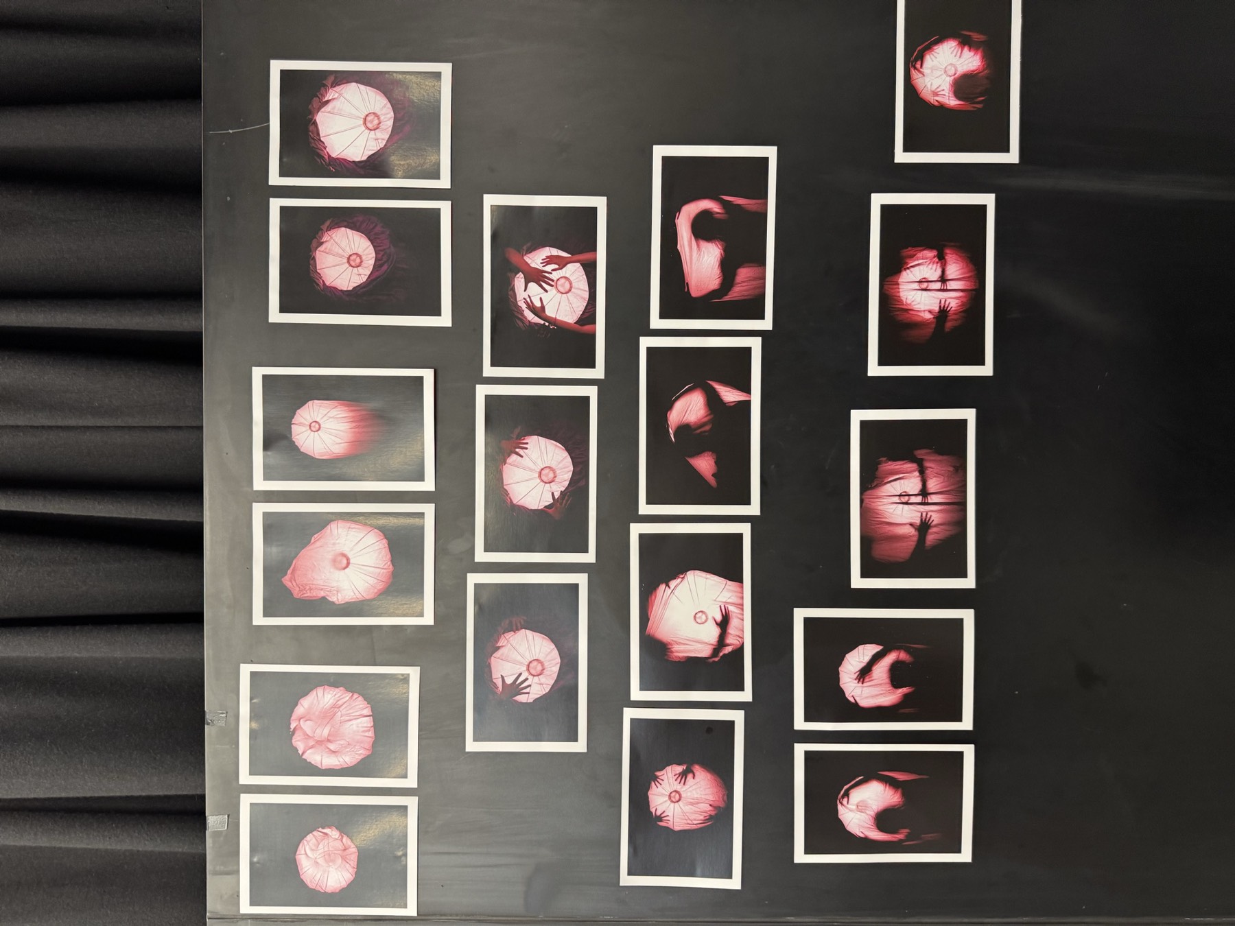 A grid of round, pink-lit photographic prints on a black wall