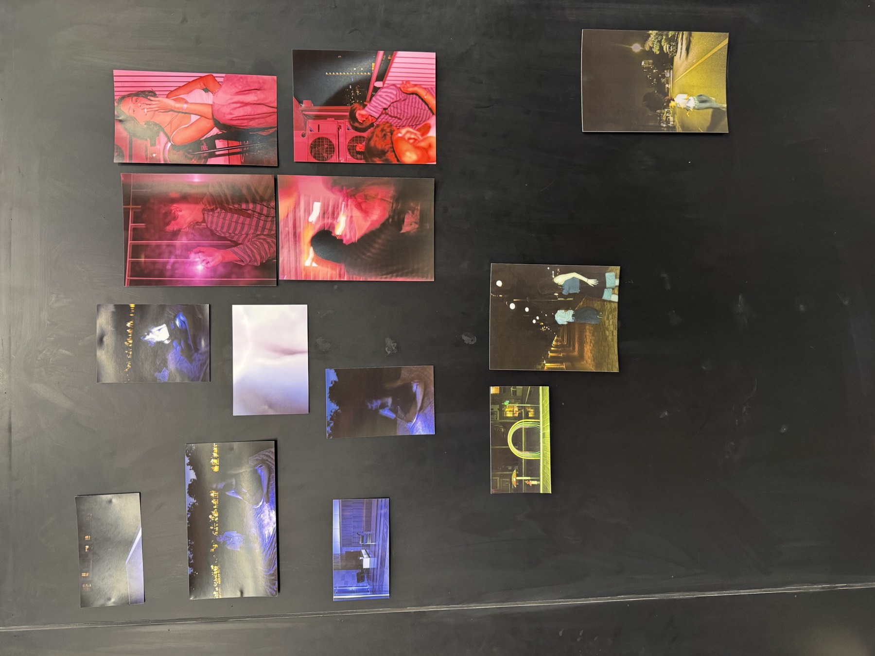 Colourful, glowing prints arranged on a dark wall