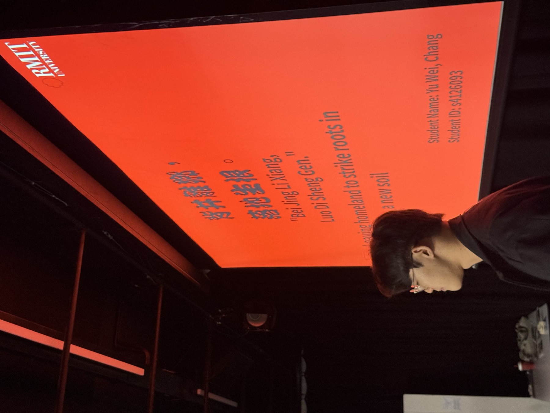 A red-lit projected text work with a viewer looking on