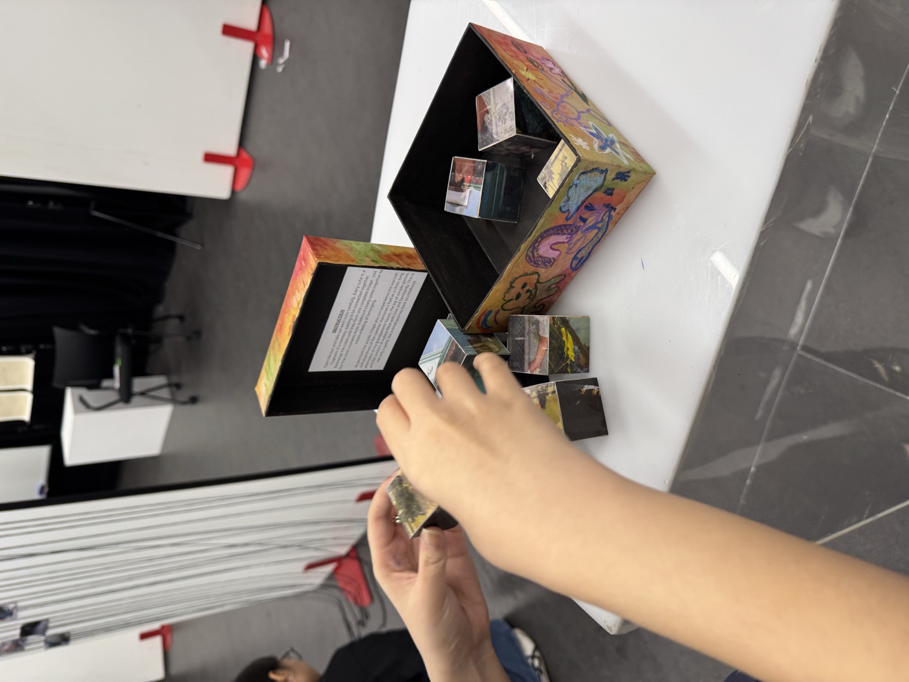 A hand placing a framed work onto a shelf